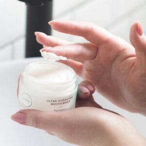 holding a jar of face moisturizer